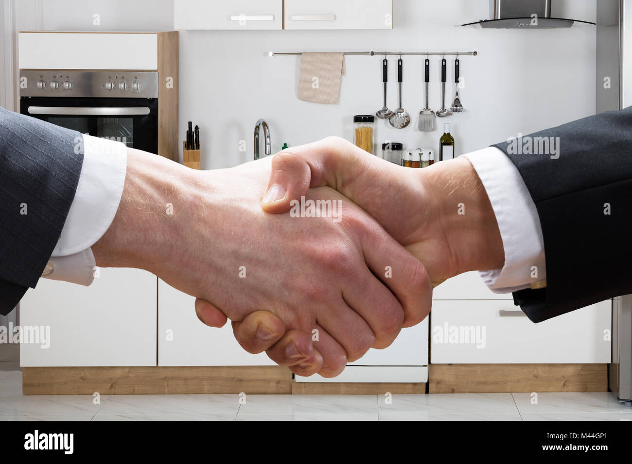 Cropped closeup of realtor shaking hands with businessman in kitchen Stock Photo