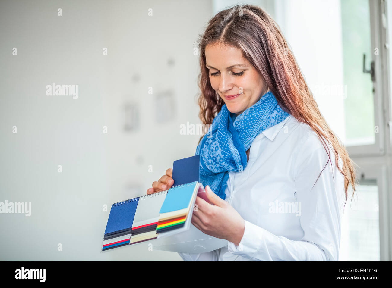 Young female fashion designer choosing blue color from swatches in office Stock Photo