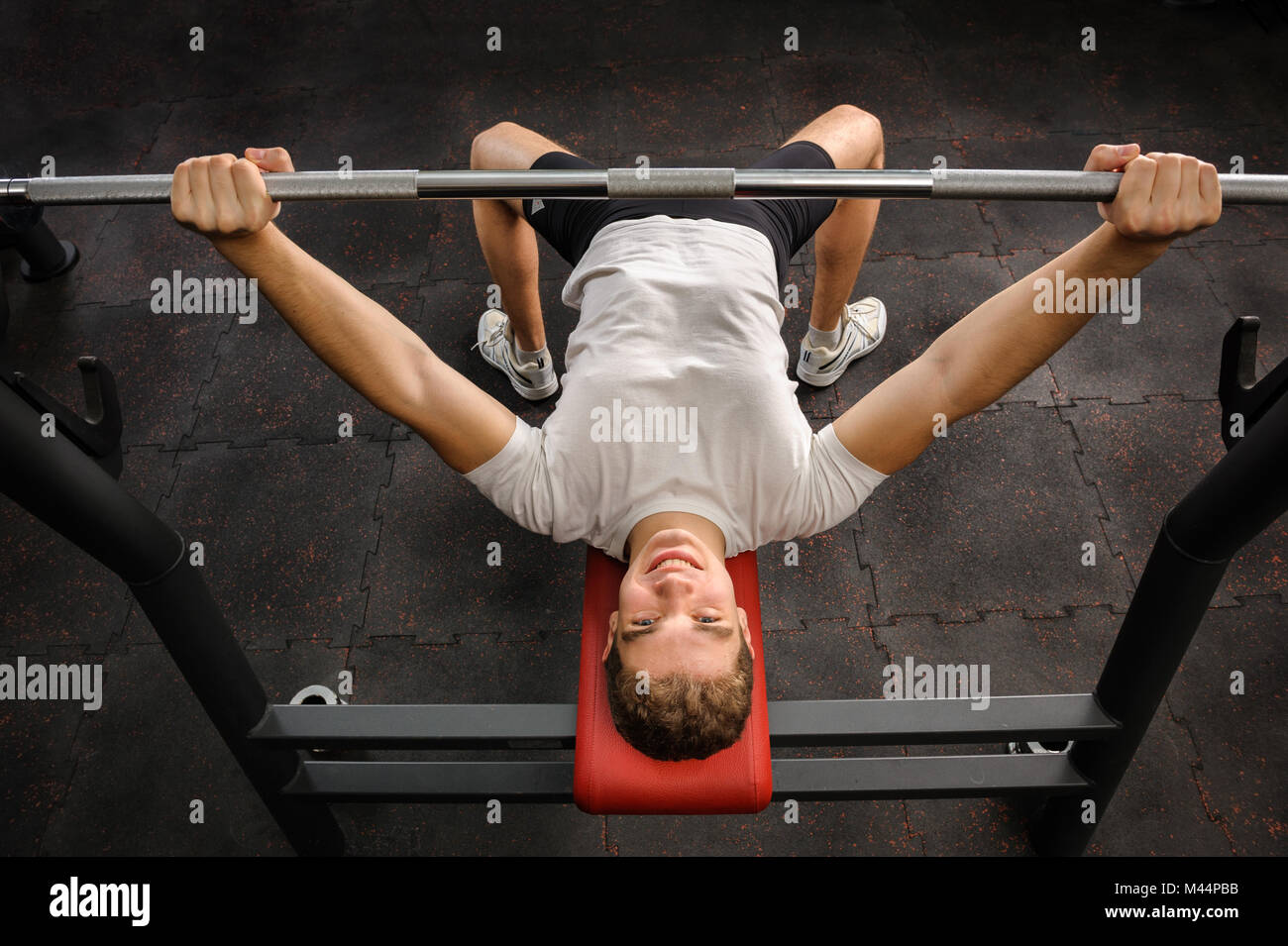 young man doing bench press workout in gym Stock Photo