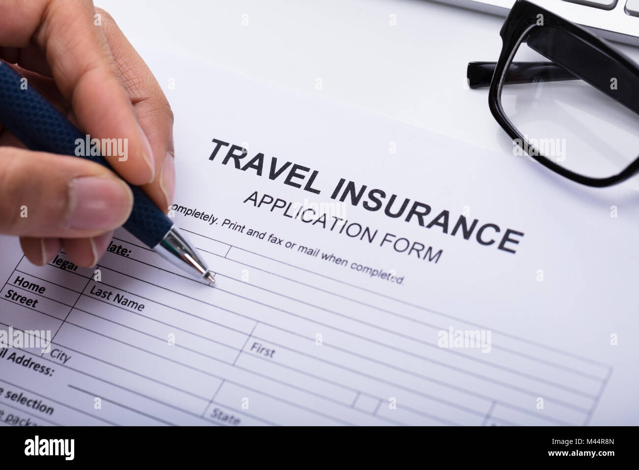 Close-up Of A Person's Hand Filling Travel Insurance Form Stock Photo