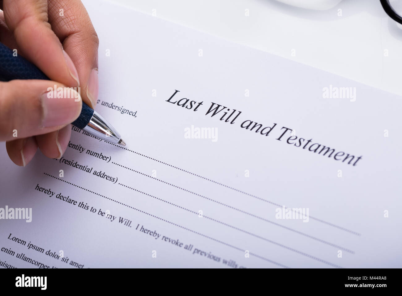 Close-up Of A Person's Hand Filling Last Will And Testament Form Stock Photo