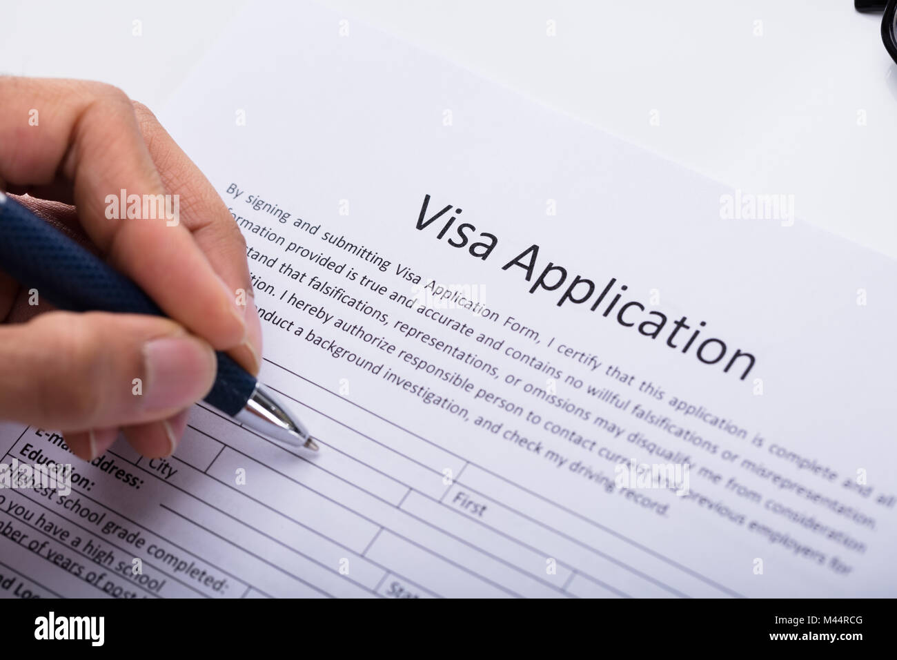 Close-up Of A Person's Hand Filling Visa Application Form Stock Photo