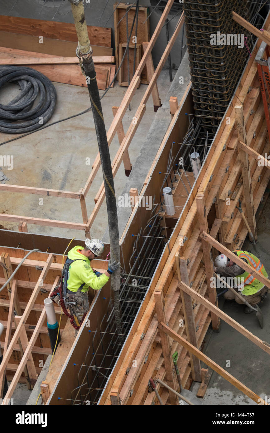 A laborer directing a hose ejecitng concrete into a mold with rebar