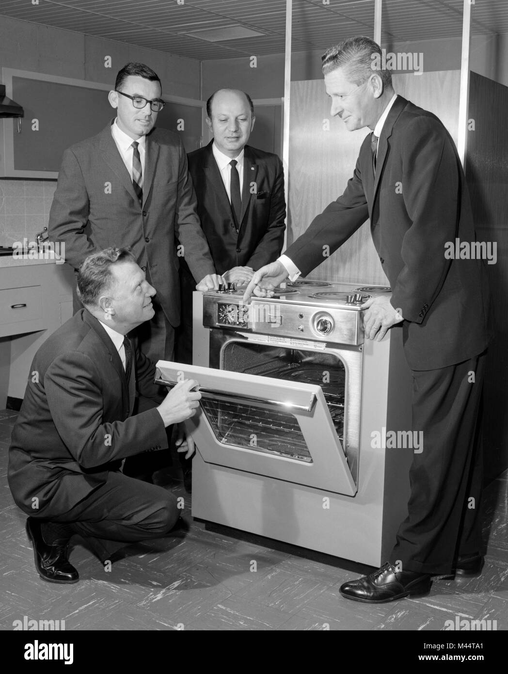 Executives check out a modern stove on a showroom floor, ca. 1962. Stock Photo