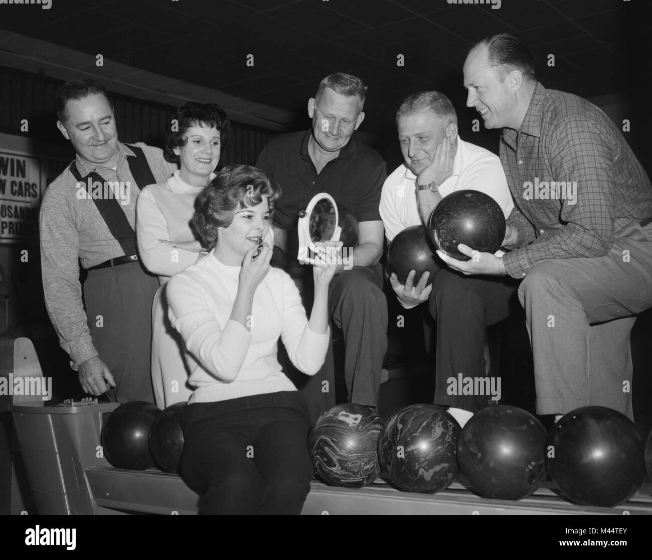 Lipstick is applied while the rest of the bowling team waits, ca. 1963. Stock Photo