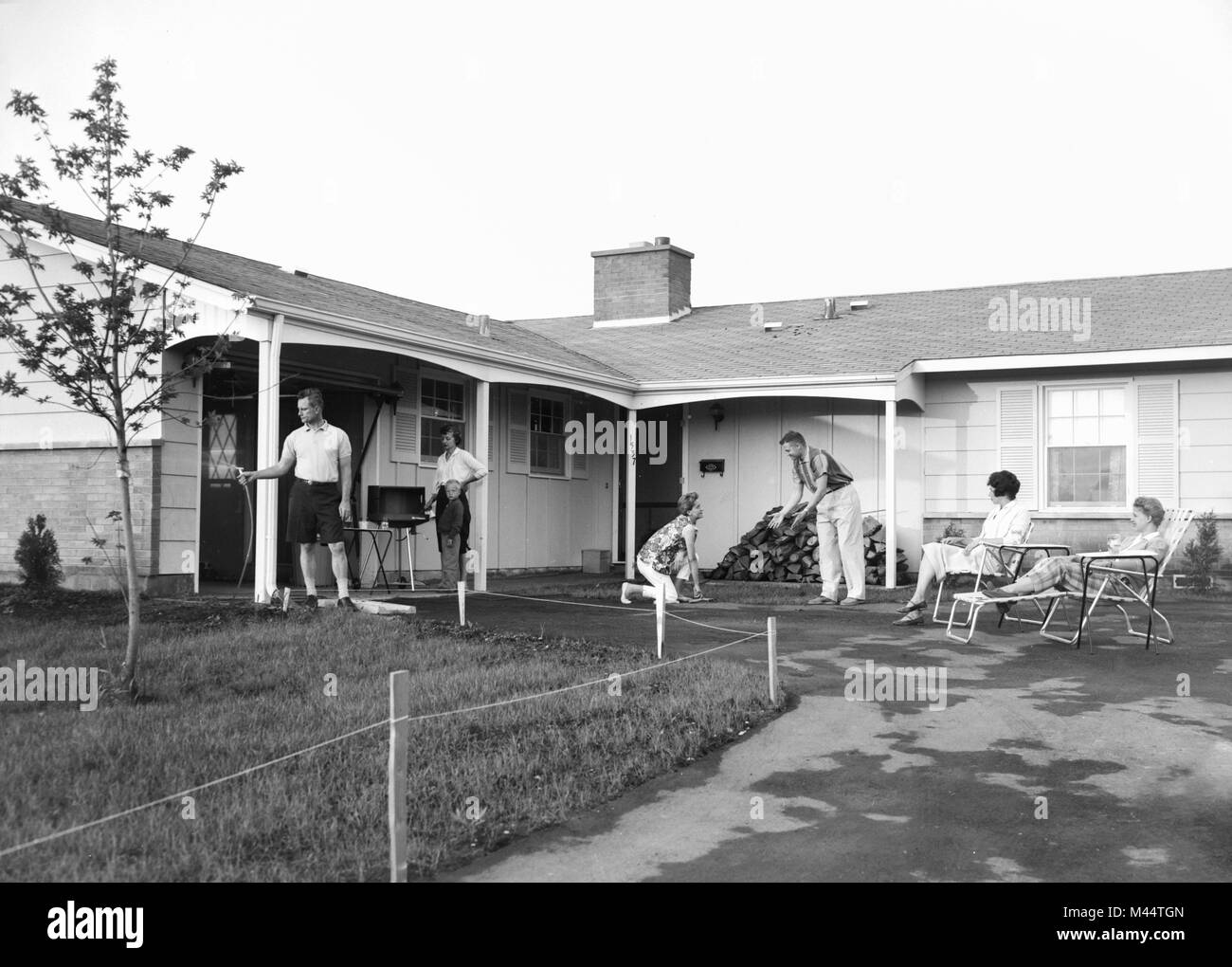 Suburban scene with neighbors getting together on the weekend, ca. 1961. Stock Photo