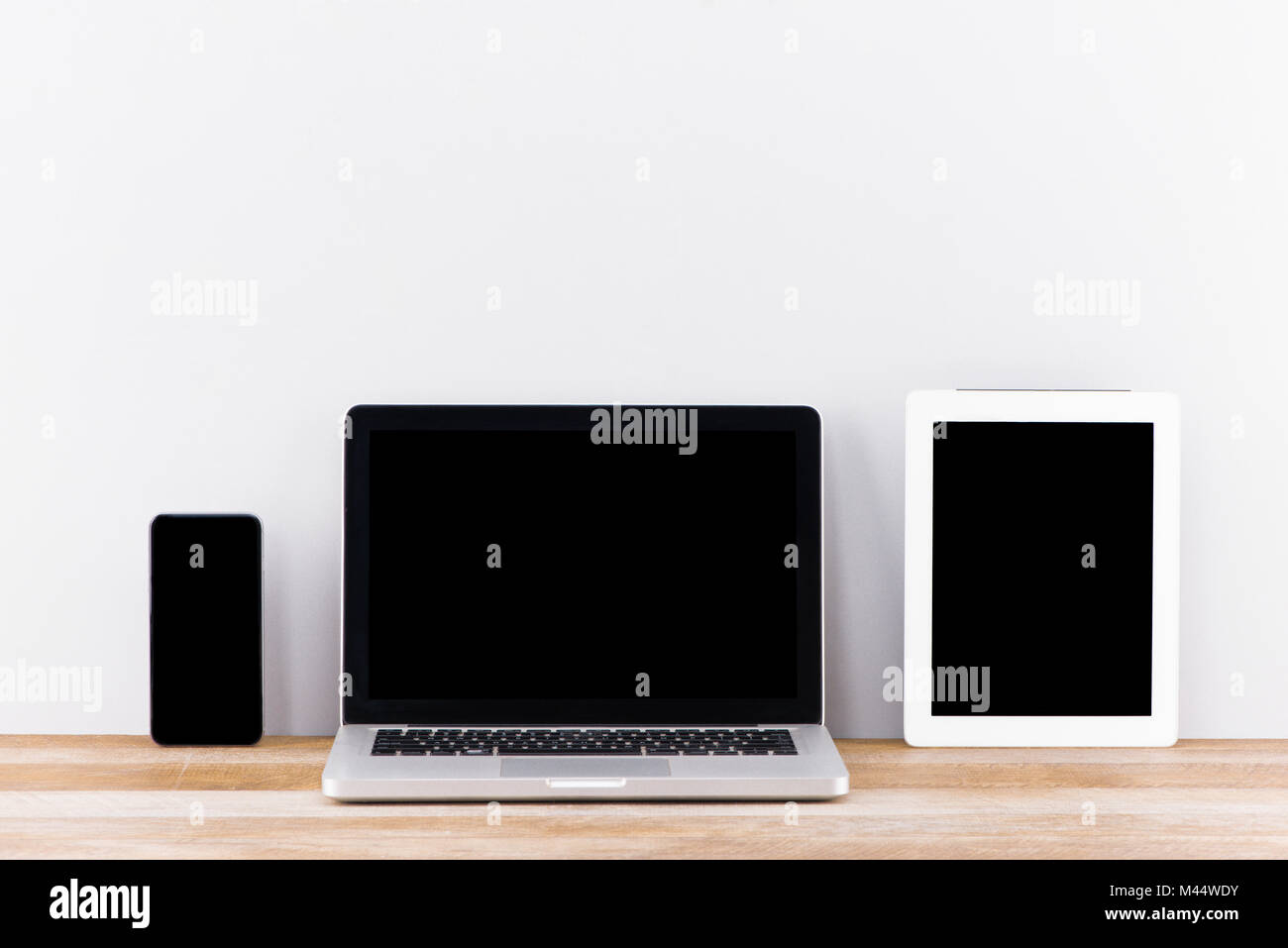 Creative web design agency presentation on multiple devices. Computer display, laptop, tablet, smart phone on white wooden desk. Brick white wall in b Stock Photo