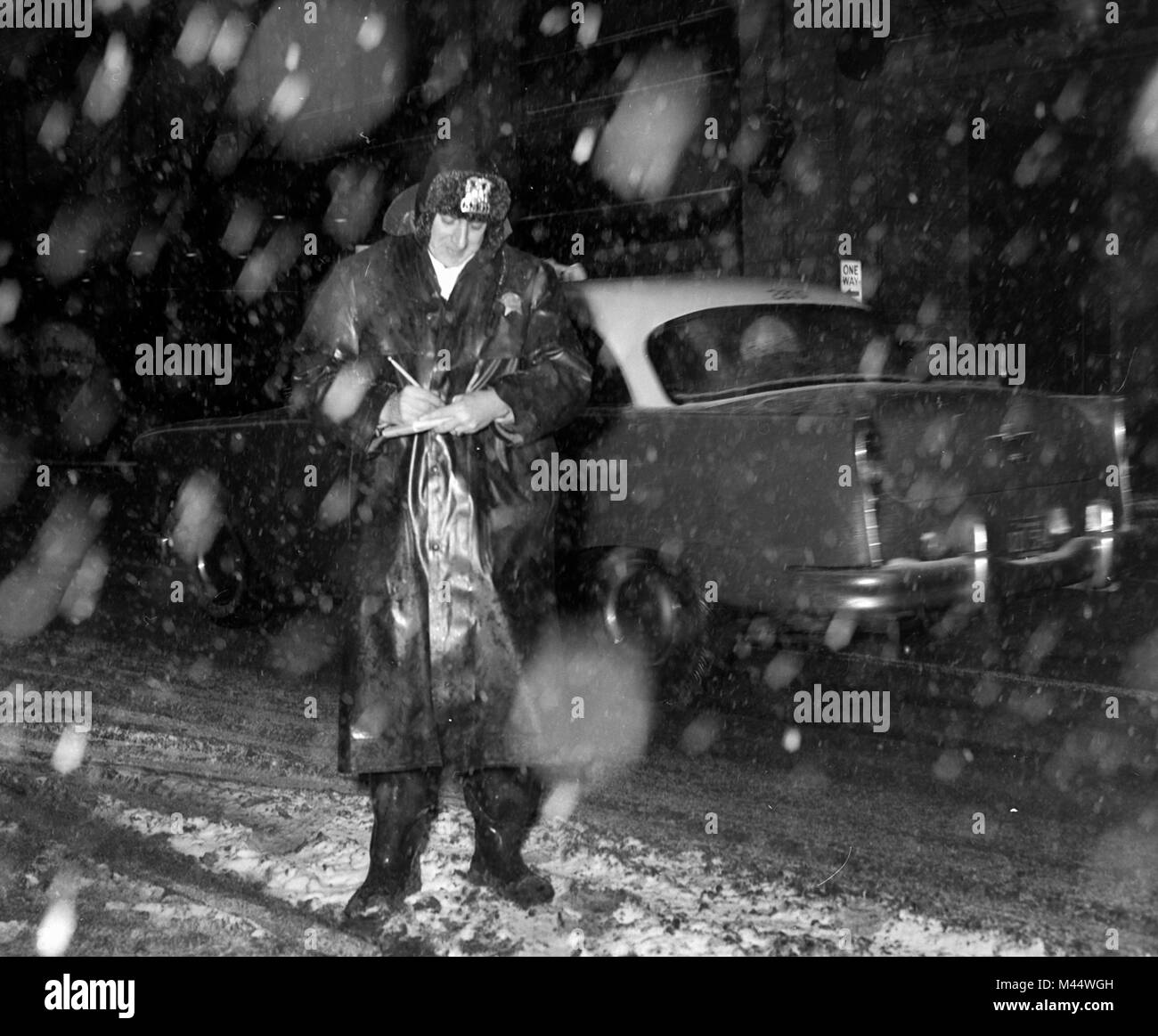 A Chicago policeman writes a parking ticket in a snowstorm in the early 1960s. Stock Photo
