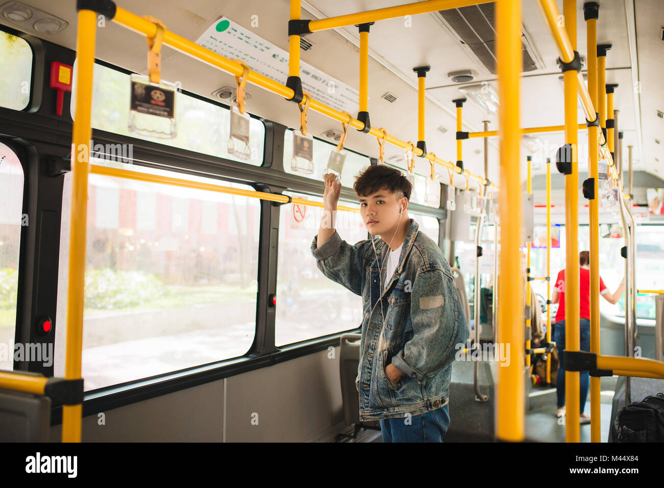 Asian man taking public transport, standing inside bus. Stock Photo