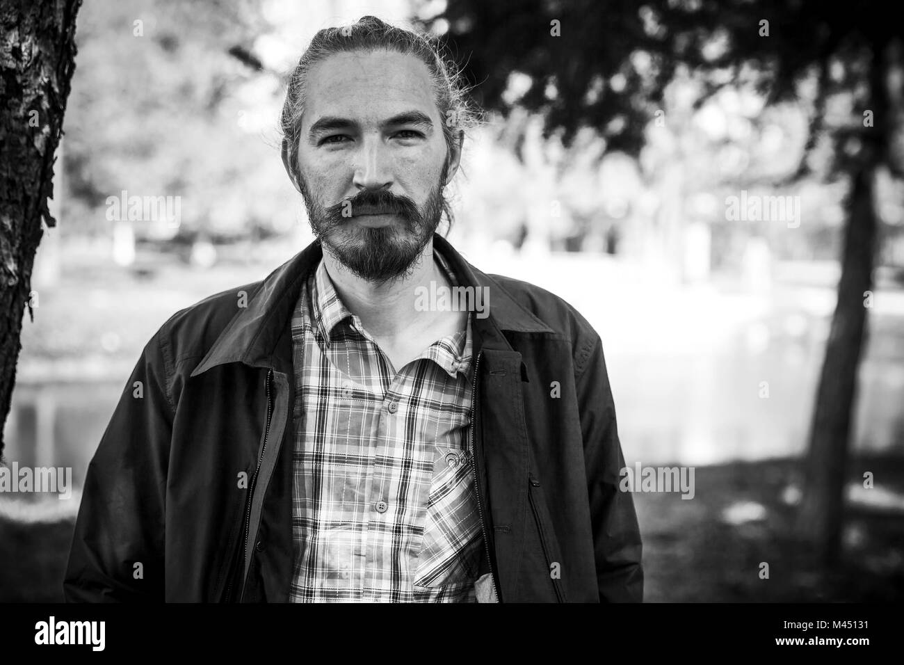 Outdoor black and white portrait of young bearded smiling man Stock Photo