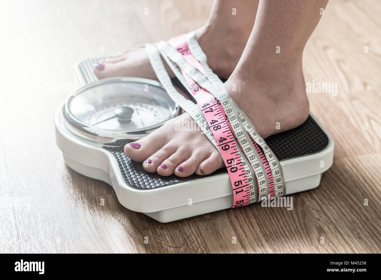 Skinny suffering female in nude underwear screaming, being tied her waist  with measuring tape posing over beige background in studio. Anorexia and  eating disorders Photos