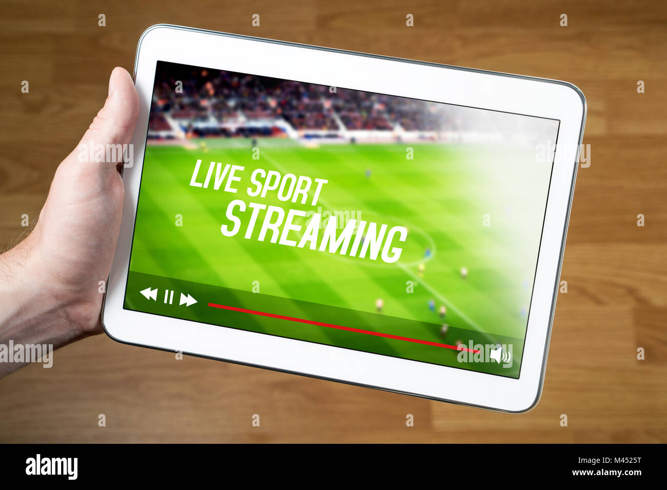 Man watching live sport stream online with mobile device. Hand holding tablet with imaginary video player and streaming service. Stock Photo