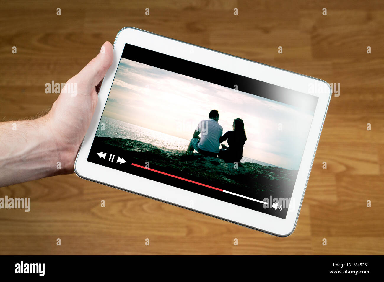 Man watching movie online with mobile device. Hand holding tablet with imaginary video player and film streaming service. Stock Photo