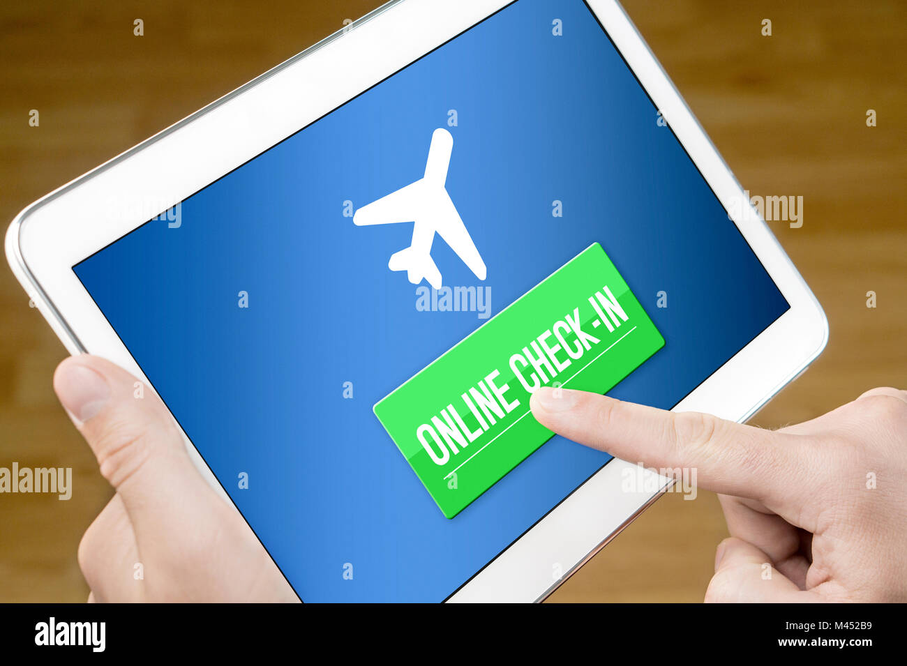 Online check in with mobile device at home. Man checking in to flight with tablet on the web. Internet self service provided by airline. Stock Photo