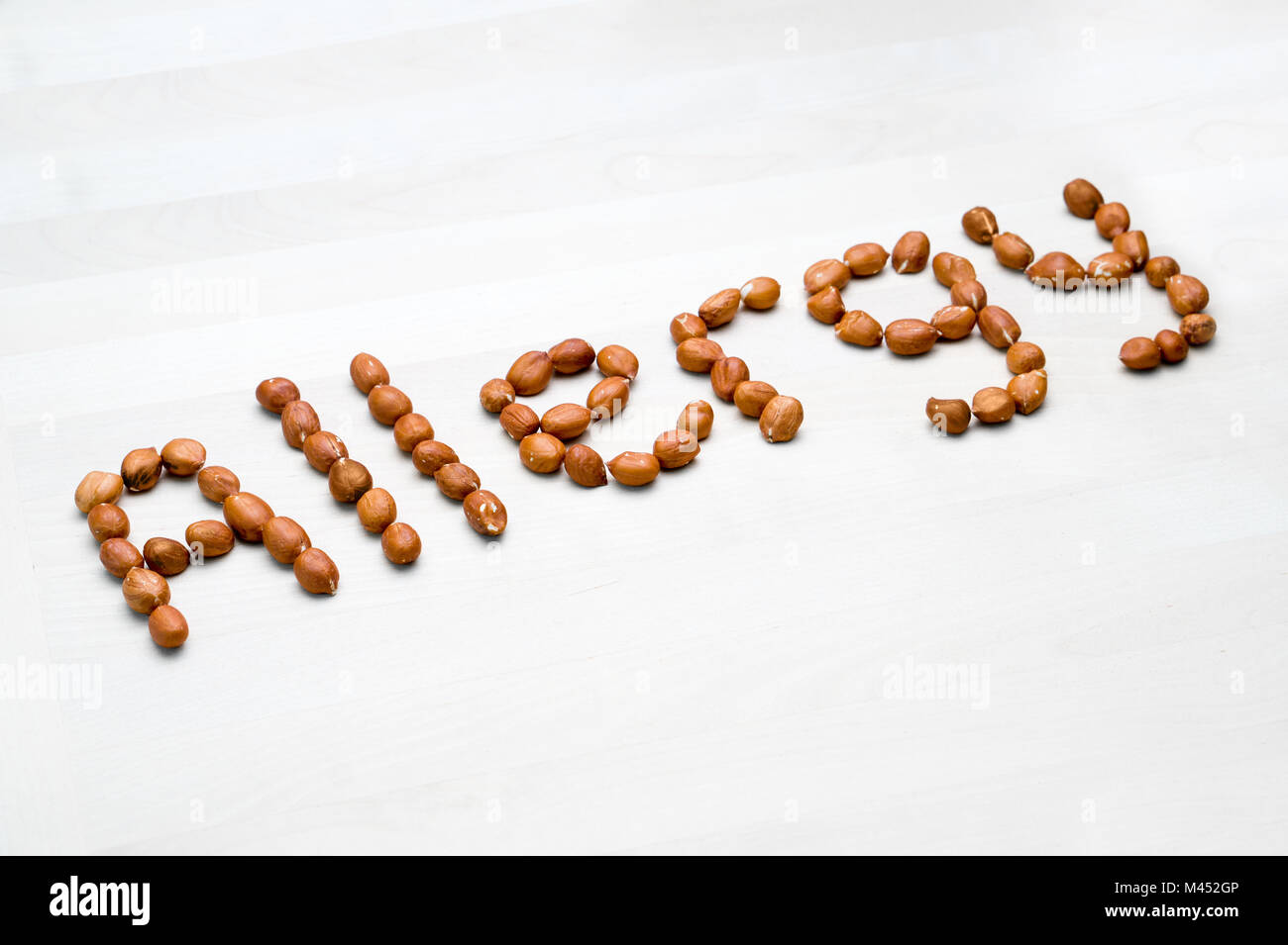 Allergy written with peanuts. Word and text made from nuts. Groundnuts on white wooden table or board. Allergic reaction and nutrition problem concept Stock Photo
