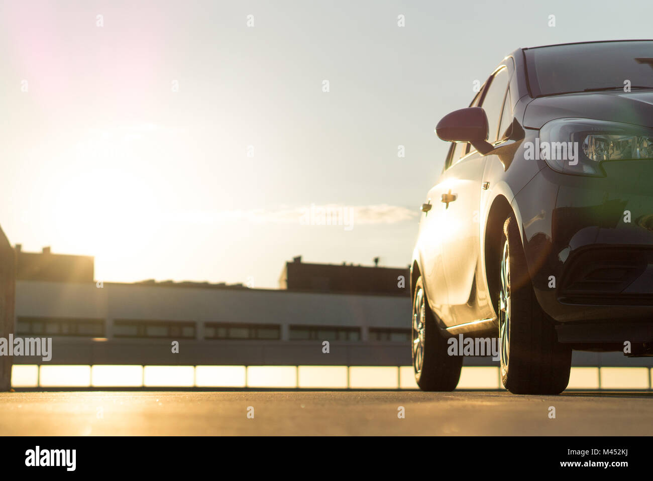 Car parked in parking lot on roof in summer time sunset or sunrise in urban city. Car background or template with copy space. Stock Photo