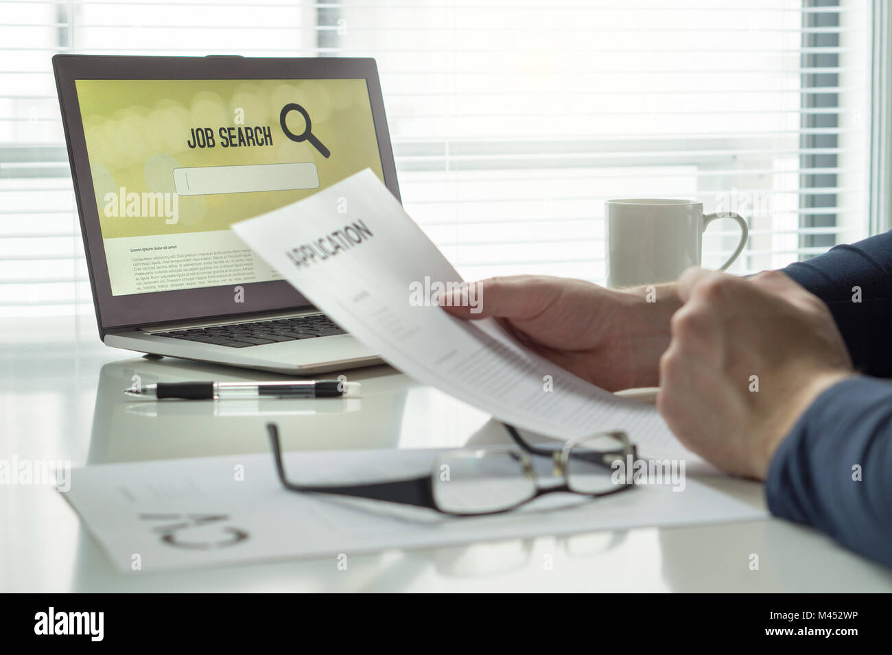 Man reading his job application paper and cv or curriculum vitae and trying to find work and get hired. Job seeker in home office. Motivated applicant Stock Photo