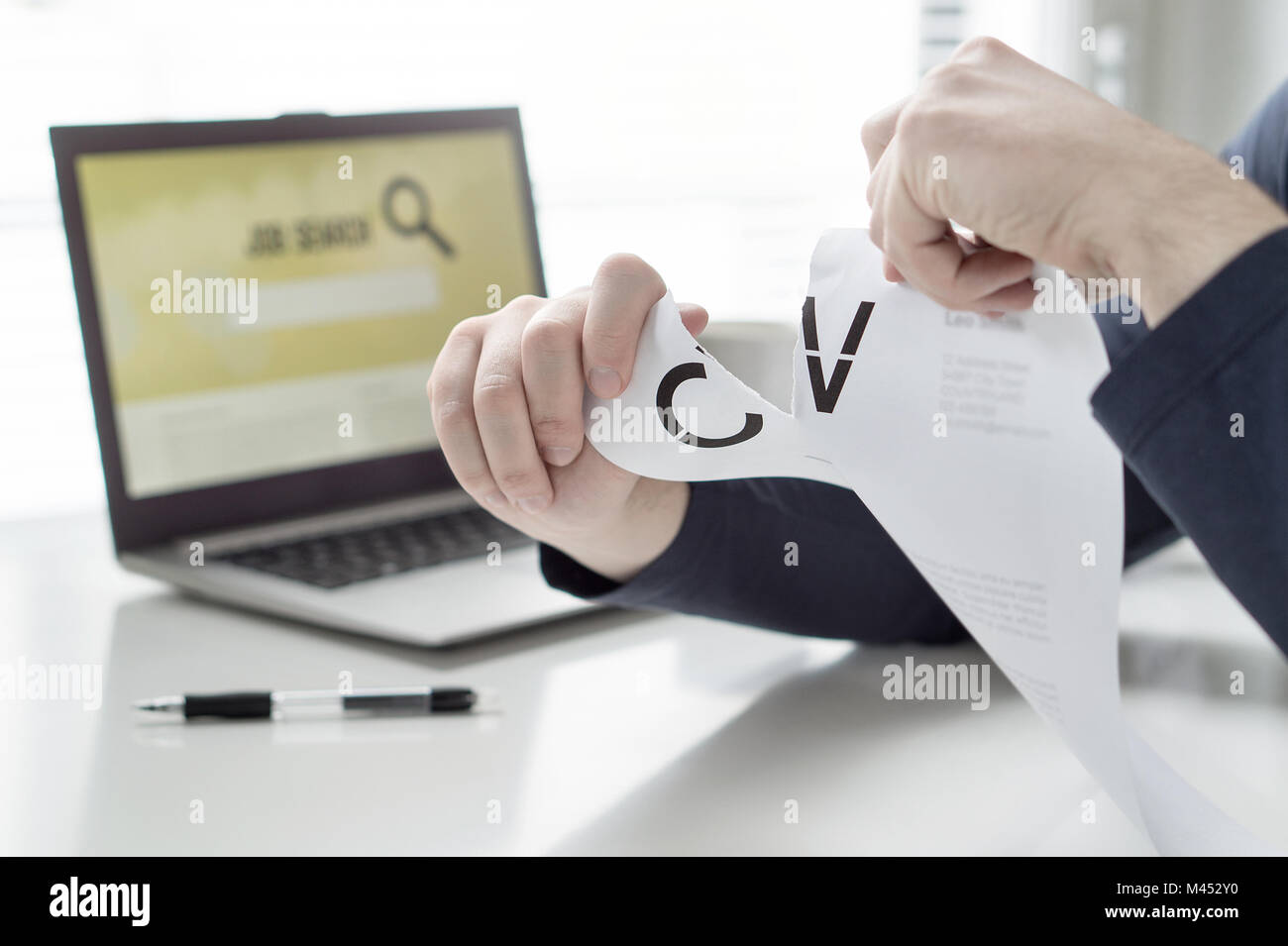 Man ripping his CV and curriculum vitae. Person having problems finding work or writing his job application paper. Angry, frustrated and tired. Stock Photo