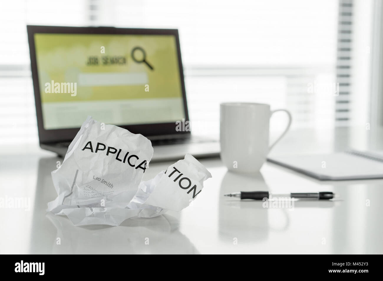 Unable to find work. Unsuccessful job search. Ripped and torn application form paper on home office table. Disappointing job seeking. Problems, anger. Stock Photo