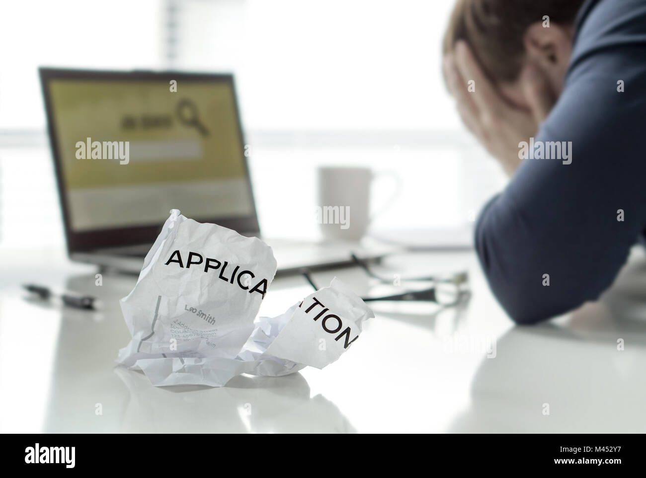Frustration in job search. Unemployed man cant' find work. Jobless, sad, confused, worried and tired person holding hands on face. Ripped application. Stock Photo