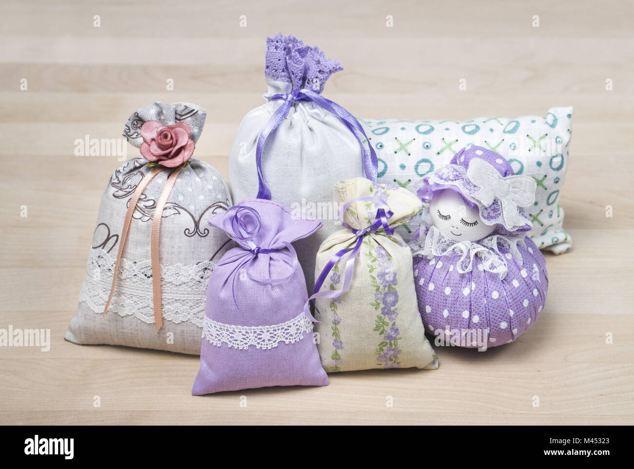 Bunch of different scented sachets for decoration on wooden board. Many fragrant pouches on table. Aromatic potpourri set. Bags filled with lavender.  Stock Photo