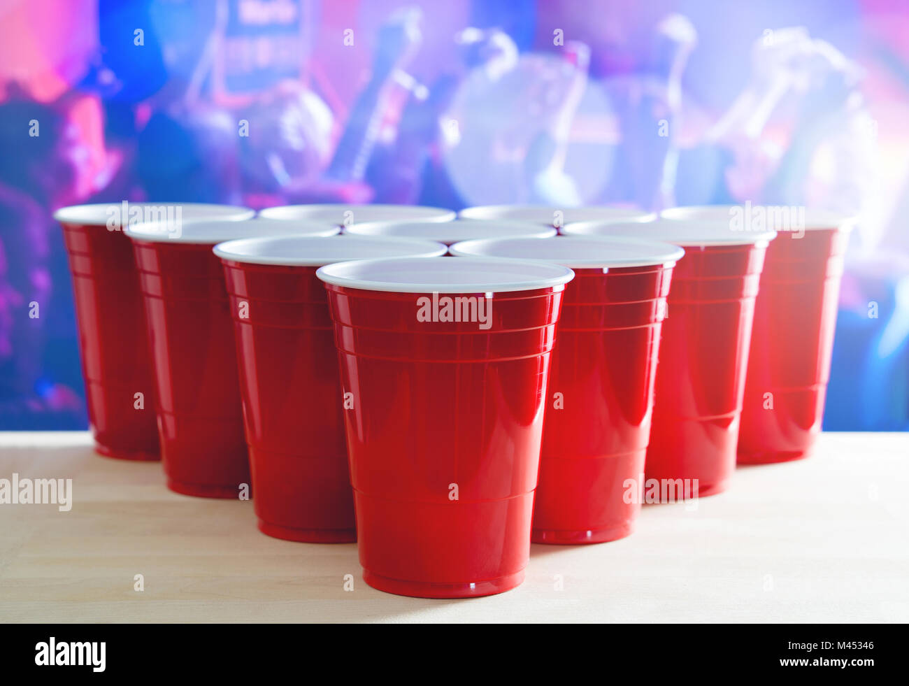 Beer pong tournament layout. Many red party cups in a nightclub full of people dancing on the dance floor in the background. Perfect for marketing. Stock Photo
