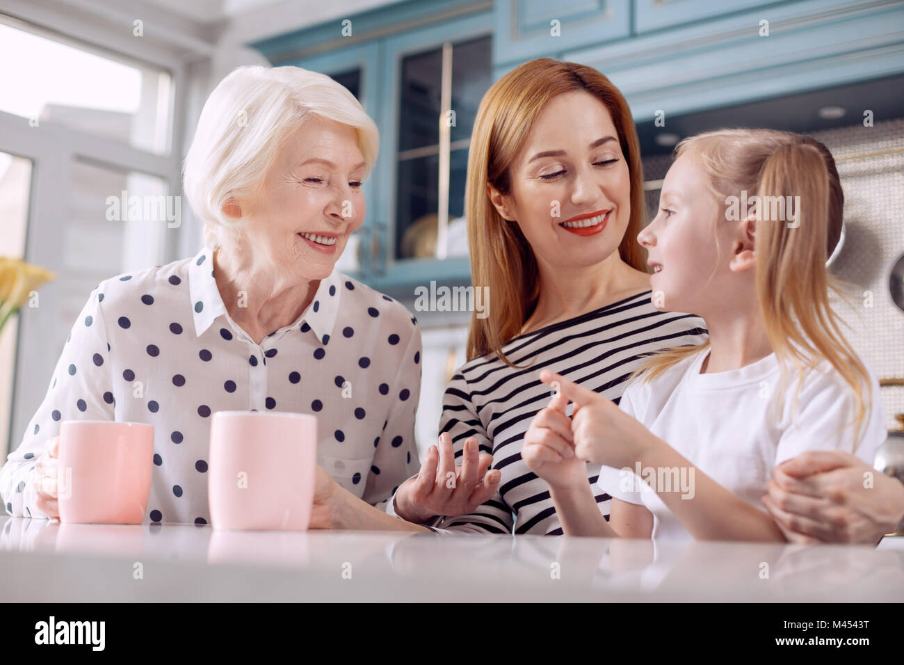 Cute girl telling funny story to her mother and grandmother Stock Photo ...