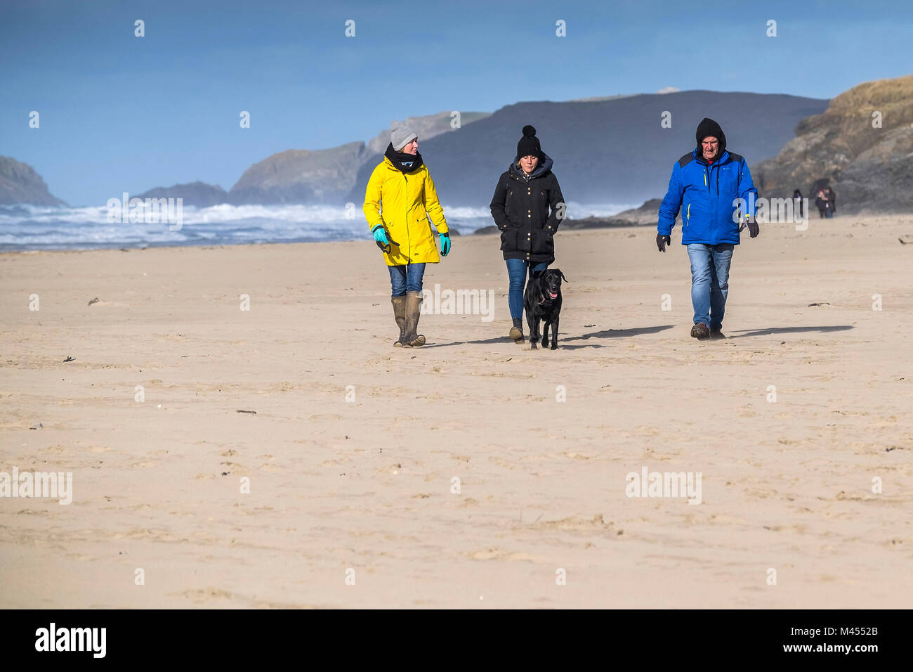 People walking a dog on Perranporth Beach in Cornwall UK. Stock Photo