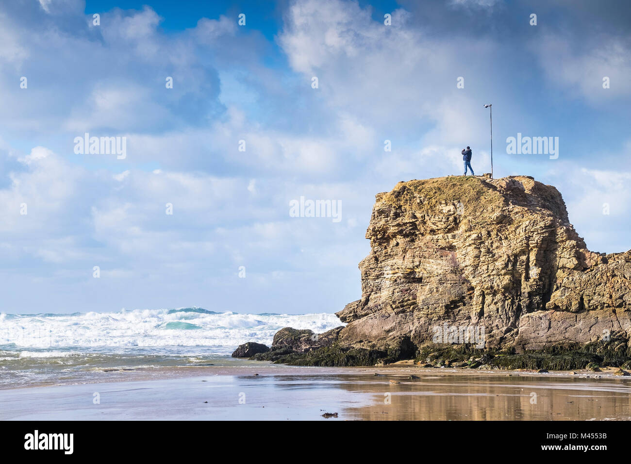 A man standing on the top of Chapel Rock Perranporth Beach in Cornwall UK. Stock Photo