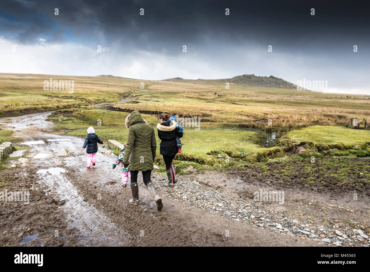 Mothers and their children toddlers walking on a muddy track at Rough Tor on Bodmin Moor in Cornwall. Stock Photo
