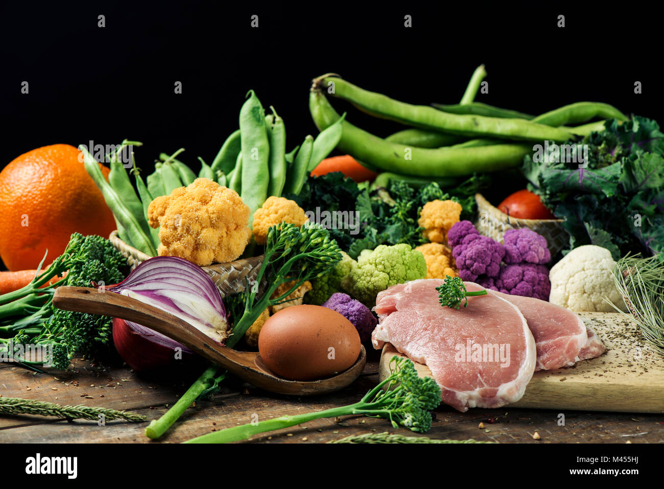 a pile of some fruit and some different raw vegetables, such as cauliflower of different colors, broccolini or french beans, and some eggs and some sl Stock Photo