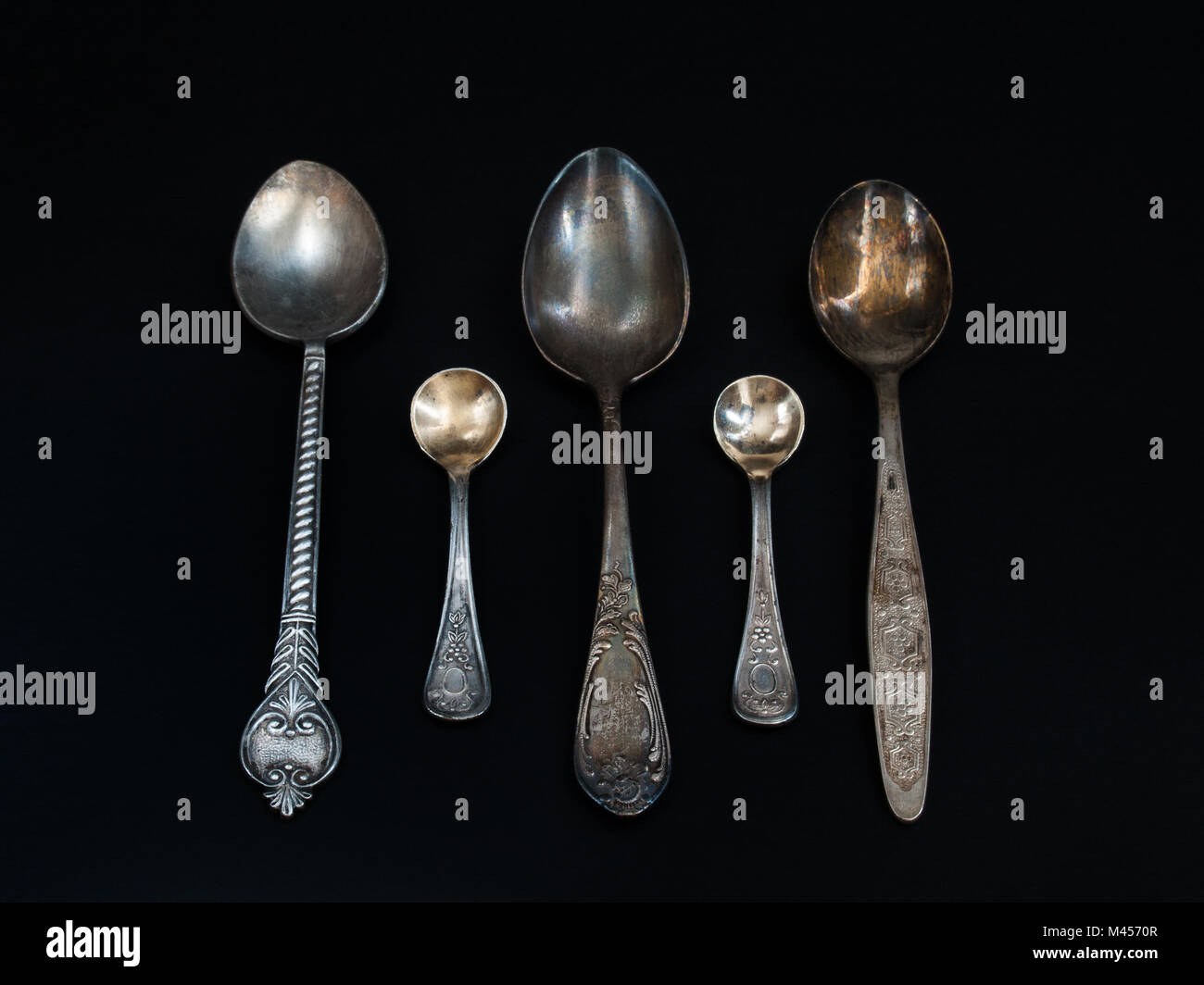 Spoons tea vintage with a pattern, engraving of different size and different shapes lie on a black background Stock Photo