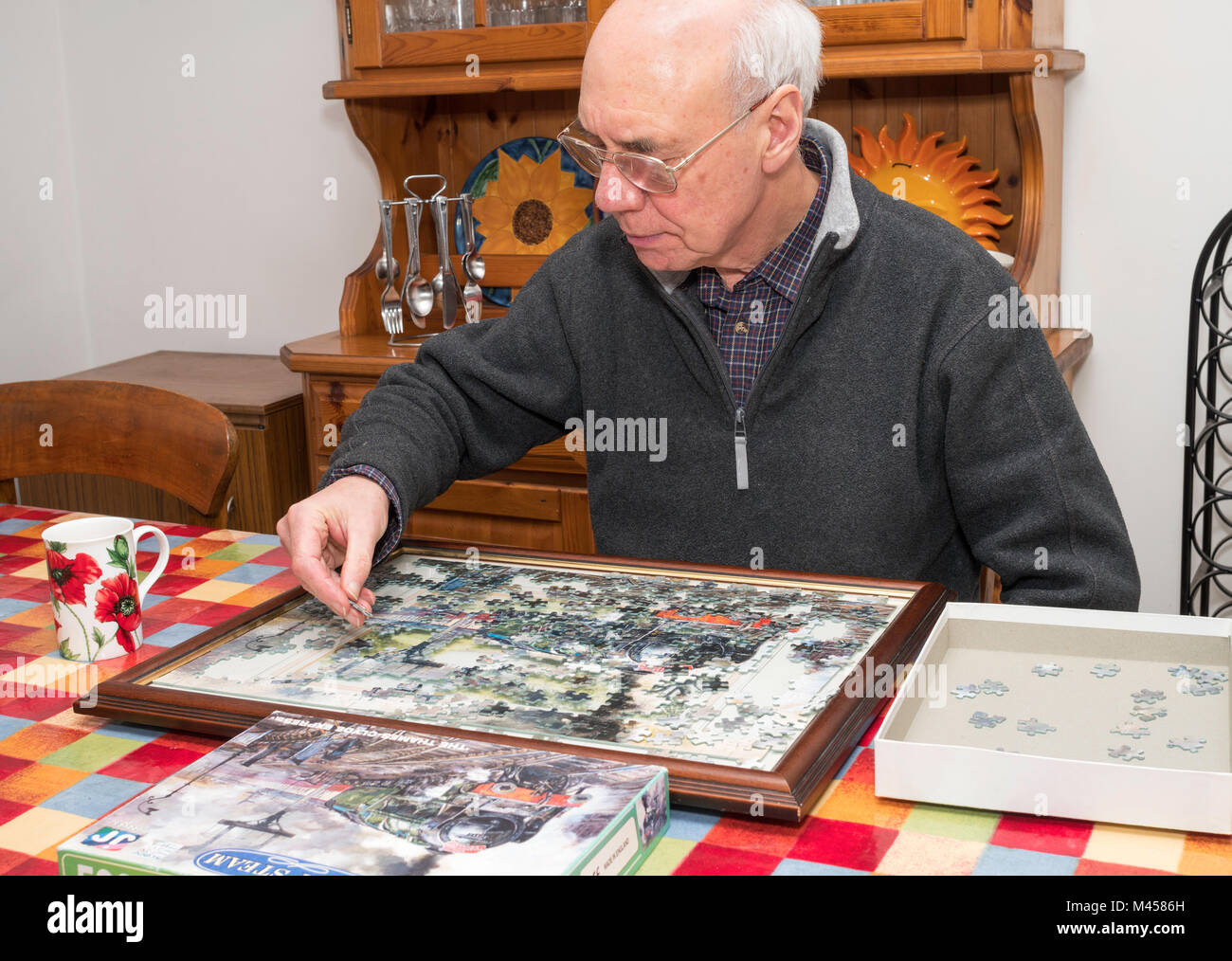 Older man completing jigsaw puzzle Stock Photo