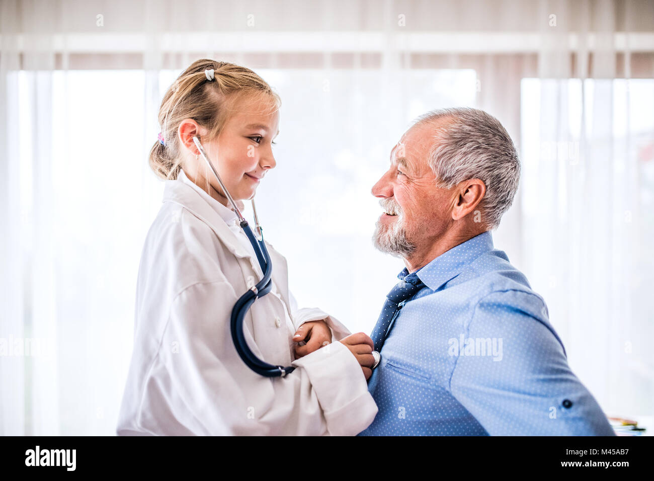 Senior doctor and a small girl with stethoscope in his office Stock ...