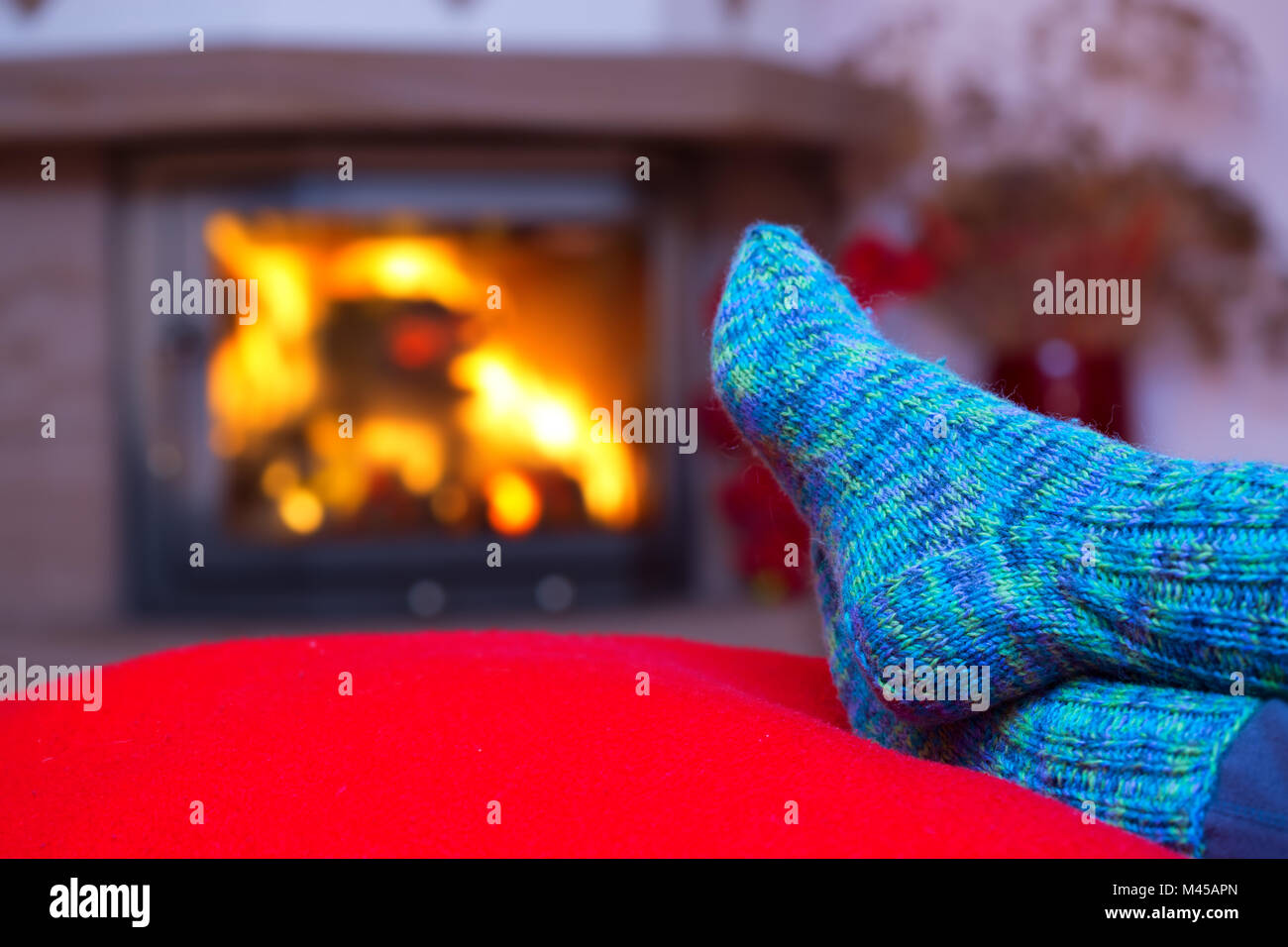 Feet in woollen blue socks by the fireplace. Stock Photo