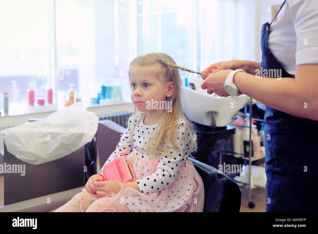 Little girl in barbershop. Making hairstyle for toddler in professional barbershop. Stock Photo