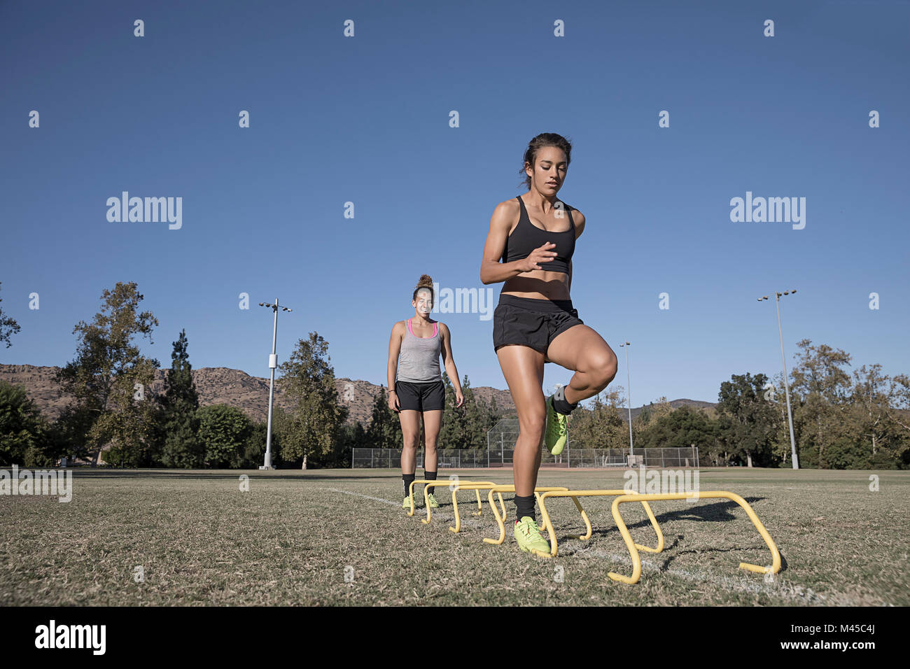 Woman jumping over agility hurdles Stock Photo