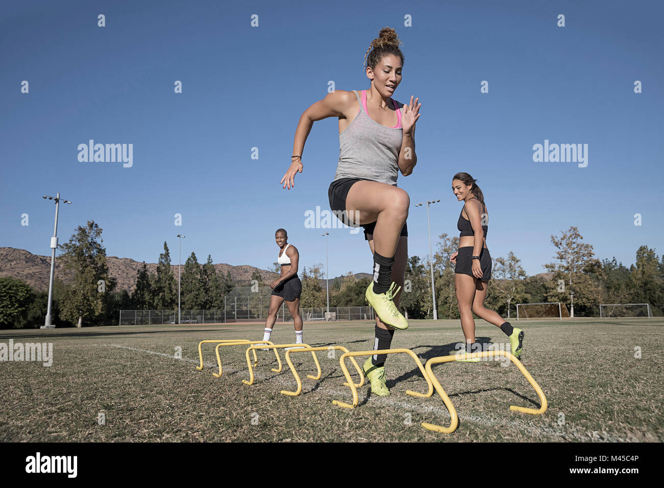 Woman jumping over agility hurdles Stock Photo