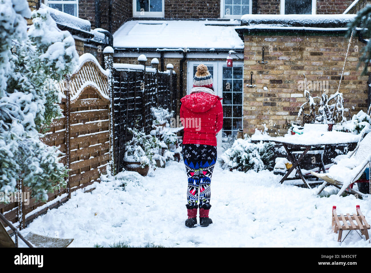 Rear view of woman standing in snow covered garden Stock Photo - Alamy