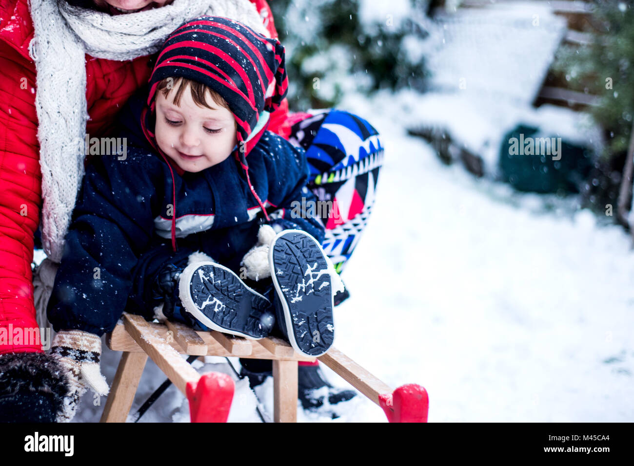 Mother and son in snow on toboggan Stock Photo