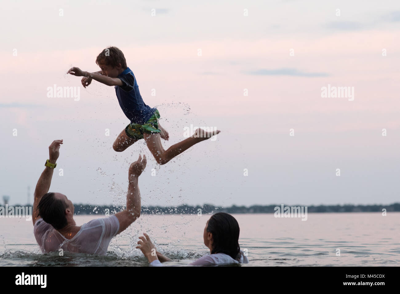 Clothed parents in water throwing son in mid air, Destin, Florida, United States, North America Stock Photo