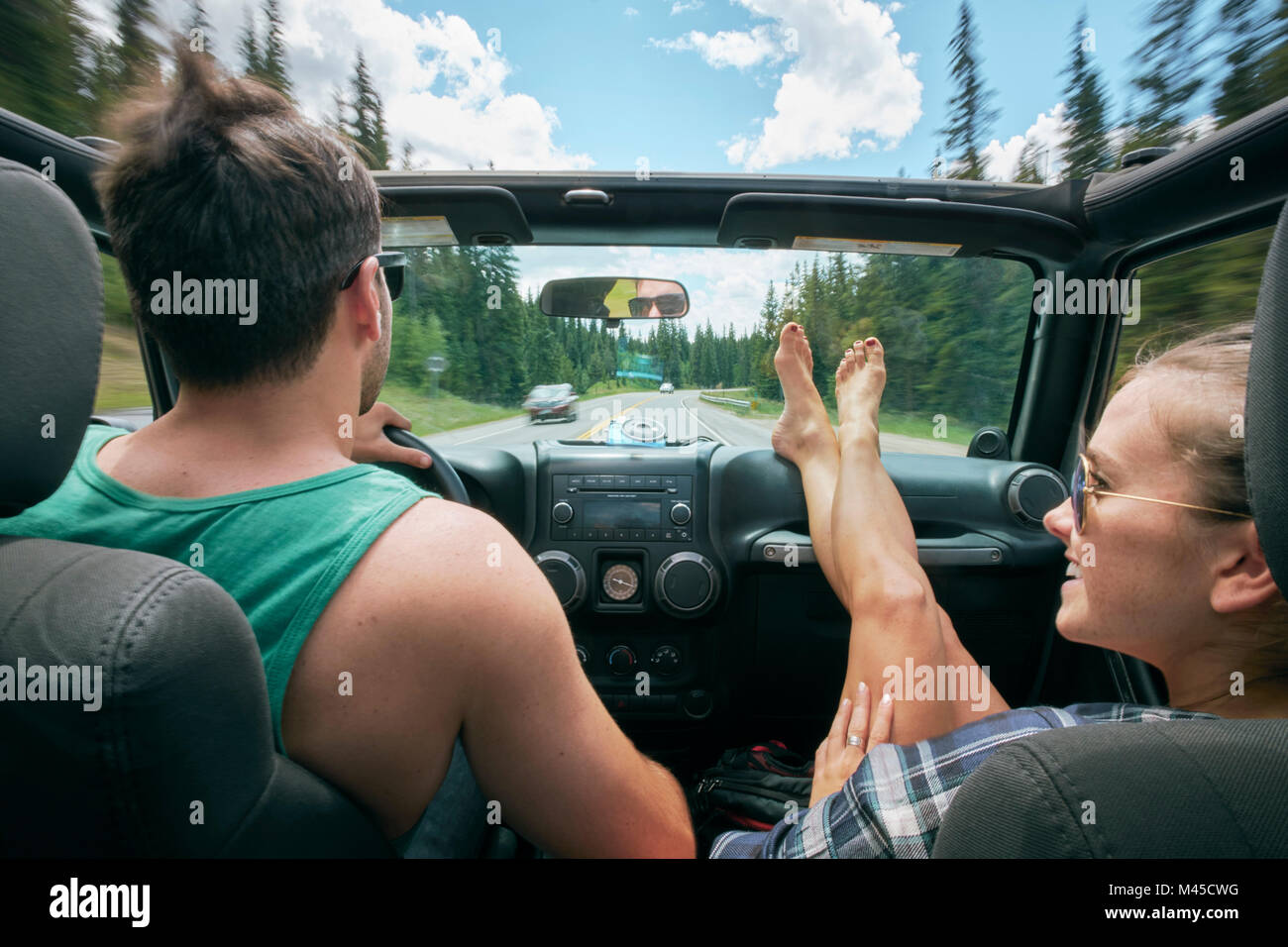 Young woman with feet up driving on road trip with boyfriend, Breckenridge, Colorado, USA Stock Photo