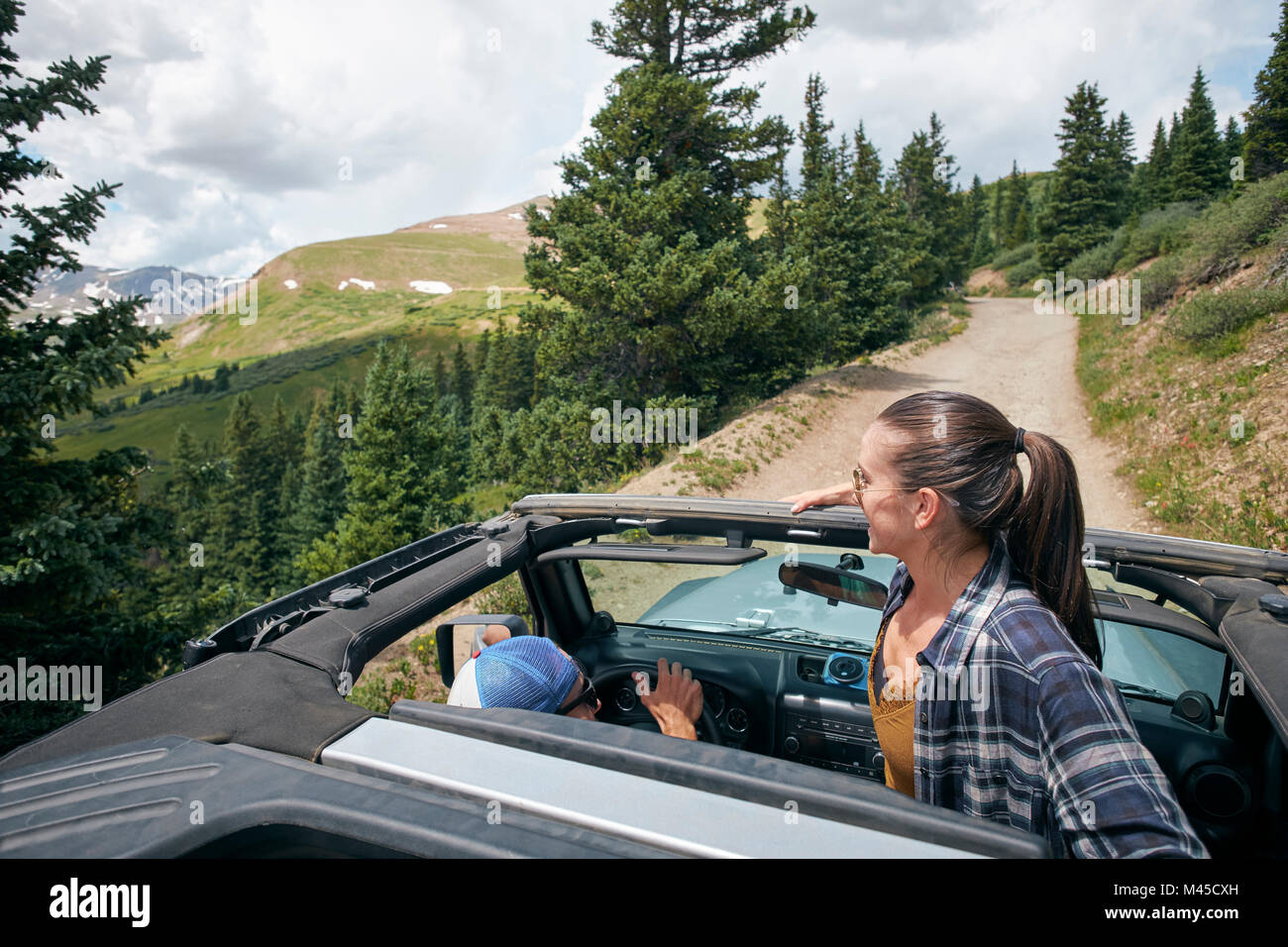 Young woman looking out from four wheel convertible in Rocky mountains