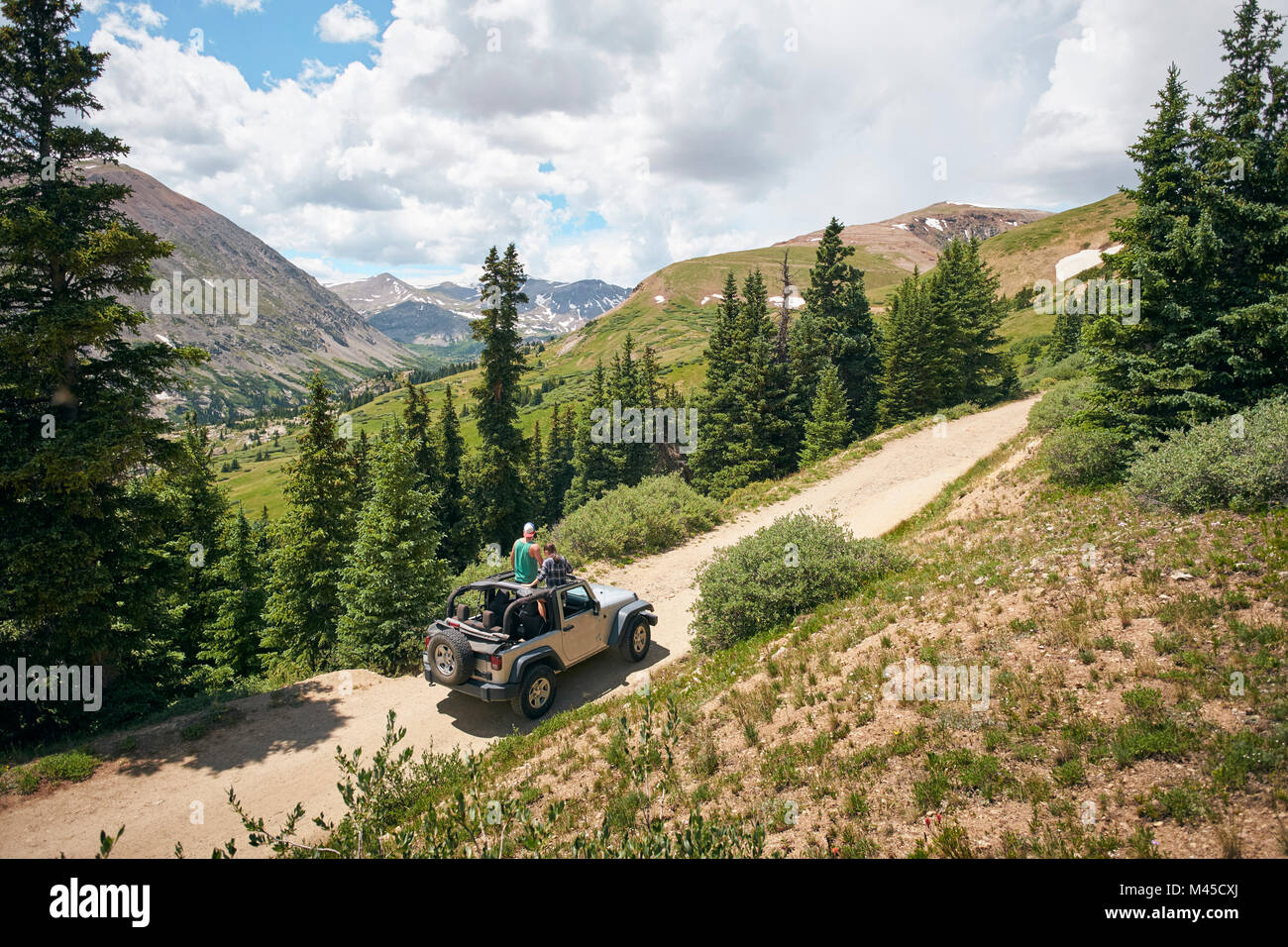 Road trip couple looking out at Rocky Mountains from four wheel