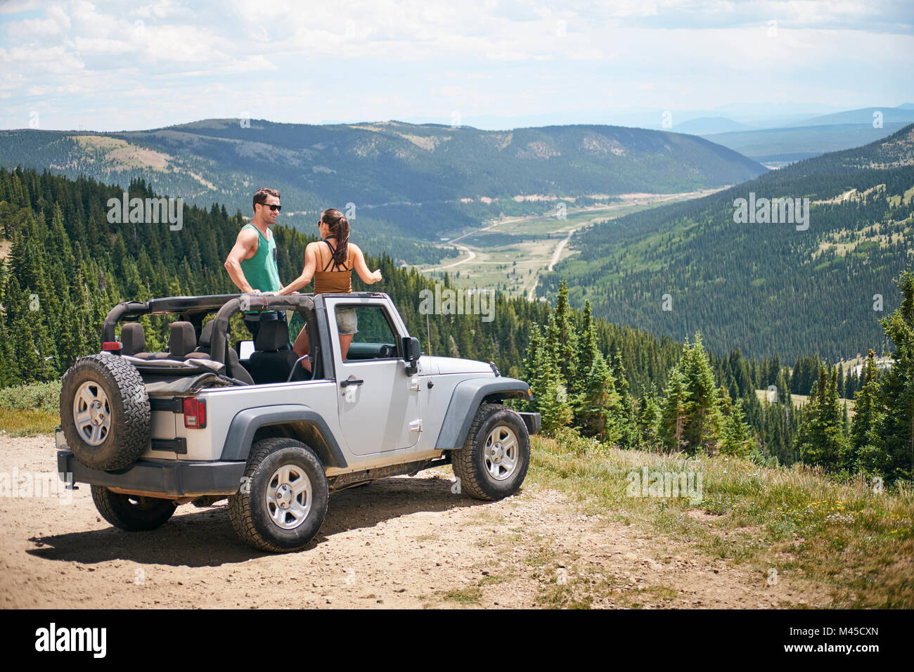 Road trip couple in parked four wheel convertible in Rocky mountains
