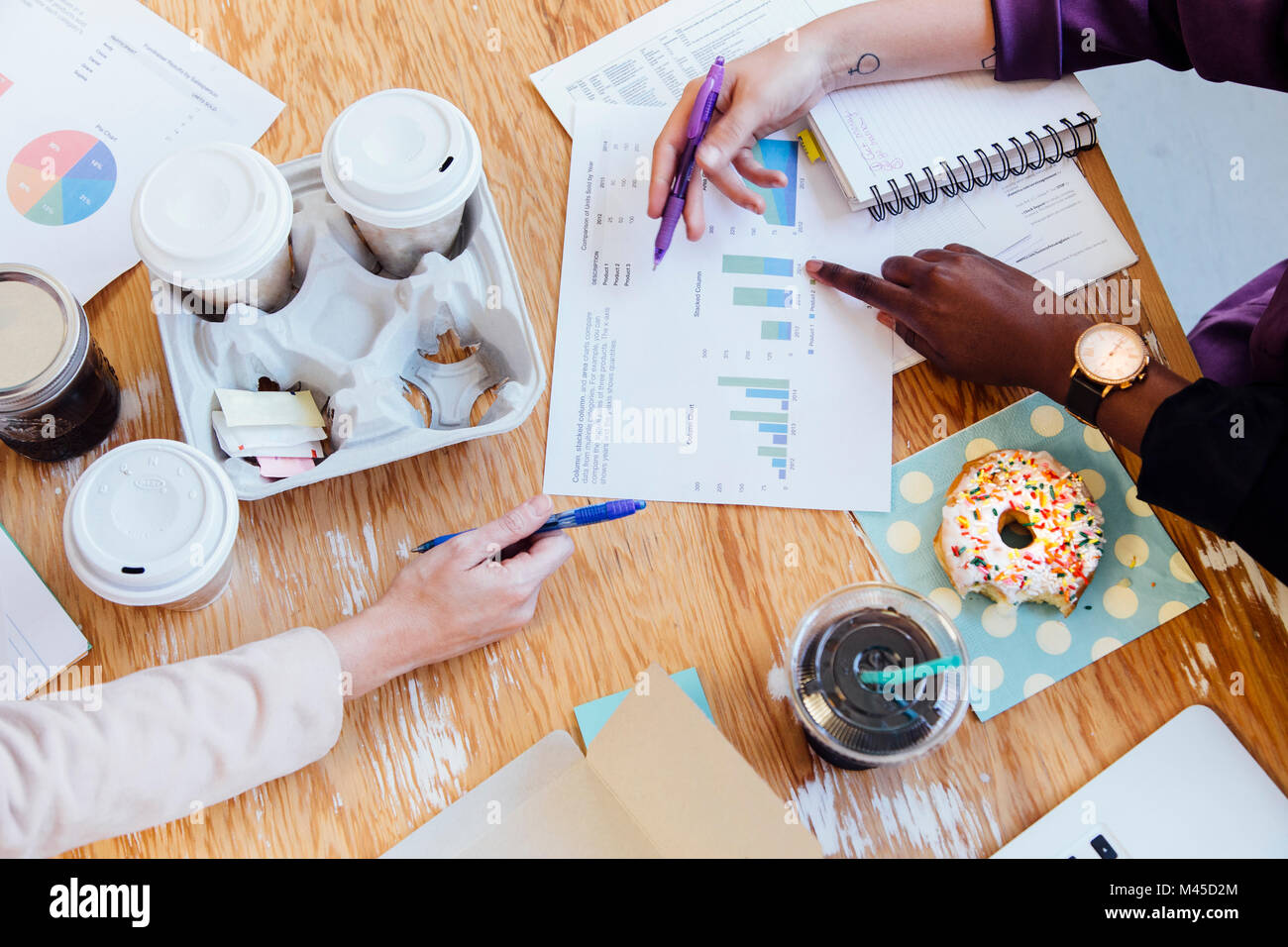 Cropped overhead view of doughnuts and coffees on desk Stock Photo