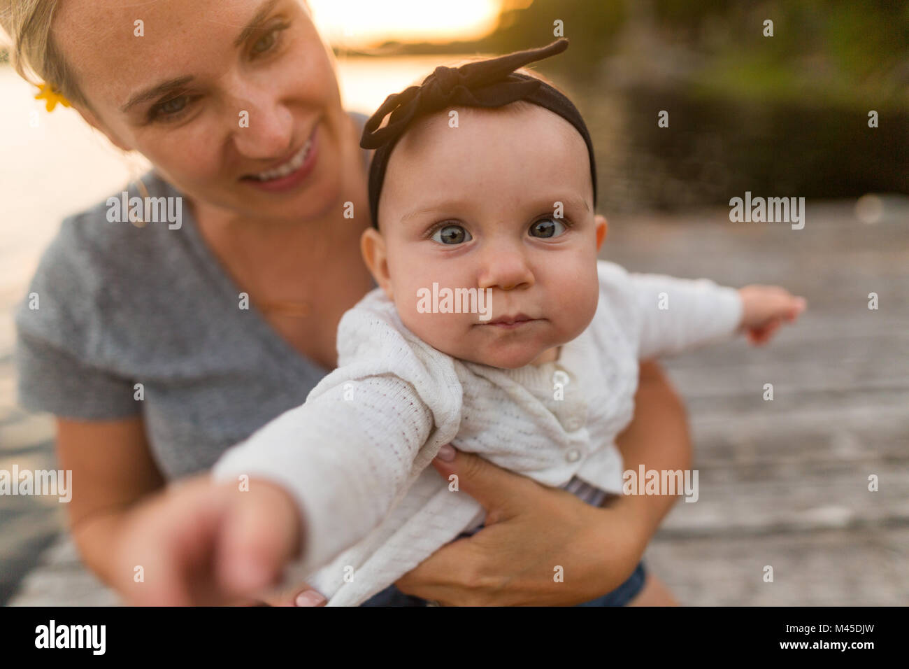 Portrait of mother carrying baby daughter on lake pier Stock Photo