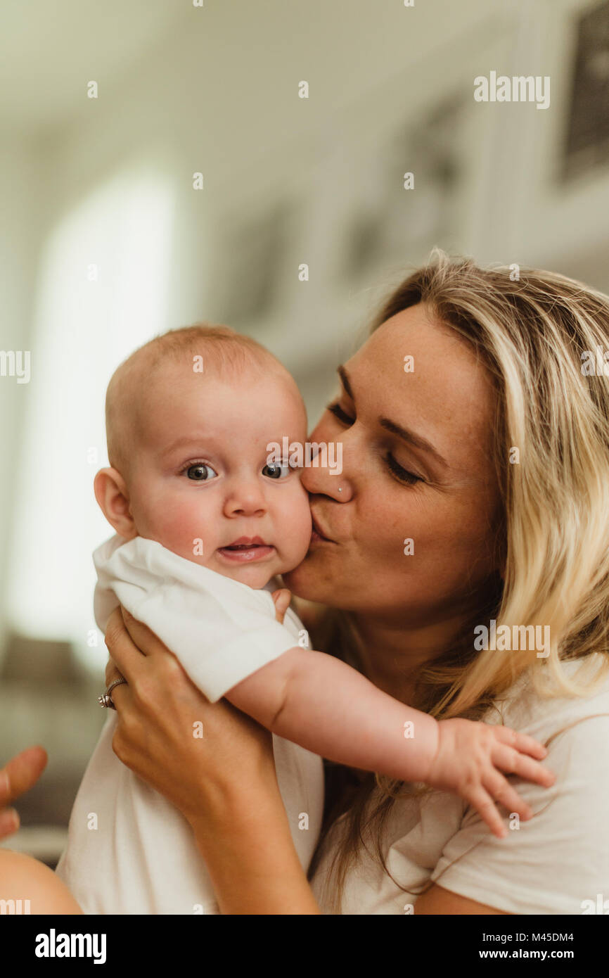 Woman kissing baby daughter on cheek Stock Photo