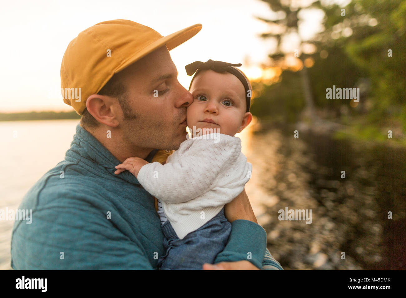 Man kissing baby daughter at lakeside Stock Photo