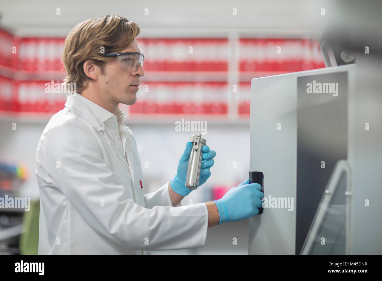 Male worker in thread factory, placing lab samples in chemical oven Stock Photo
